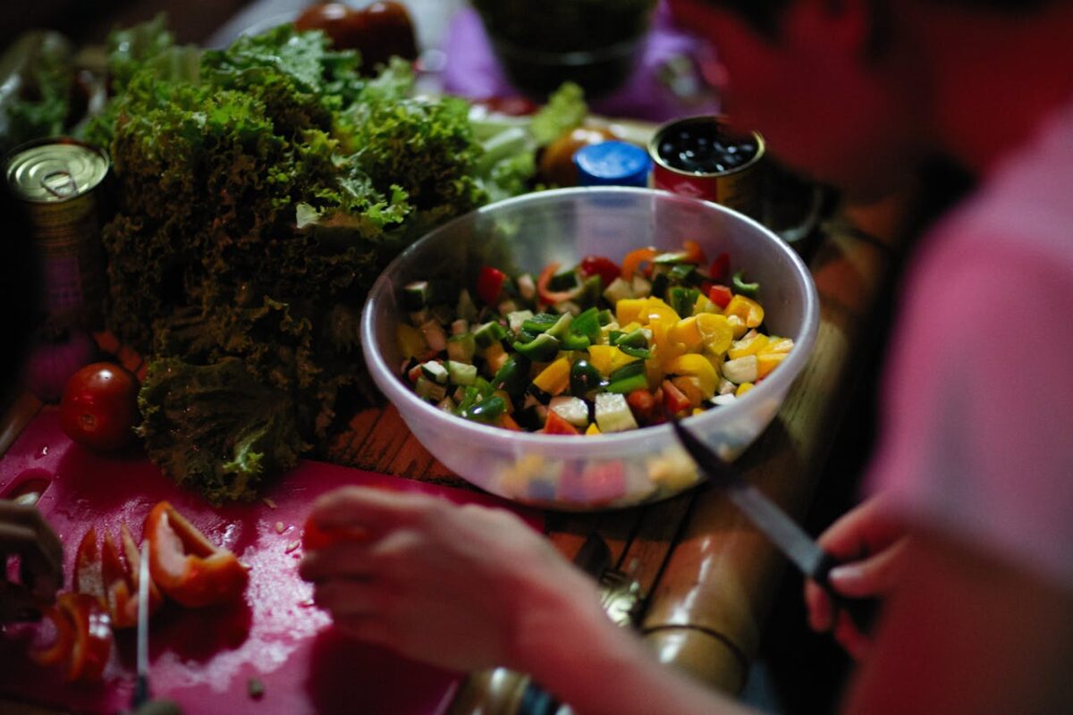 A vibrant salad with fresh diced vegetables being prepared indoors.