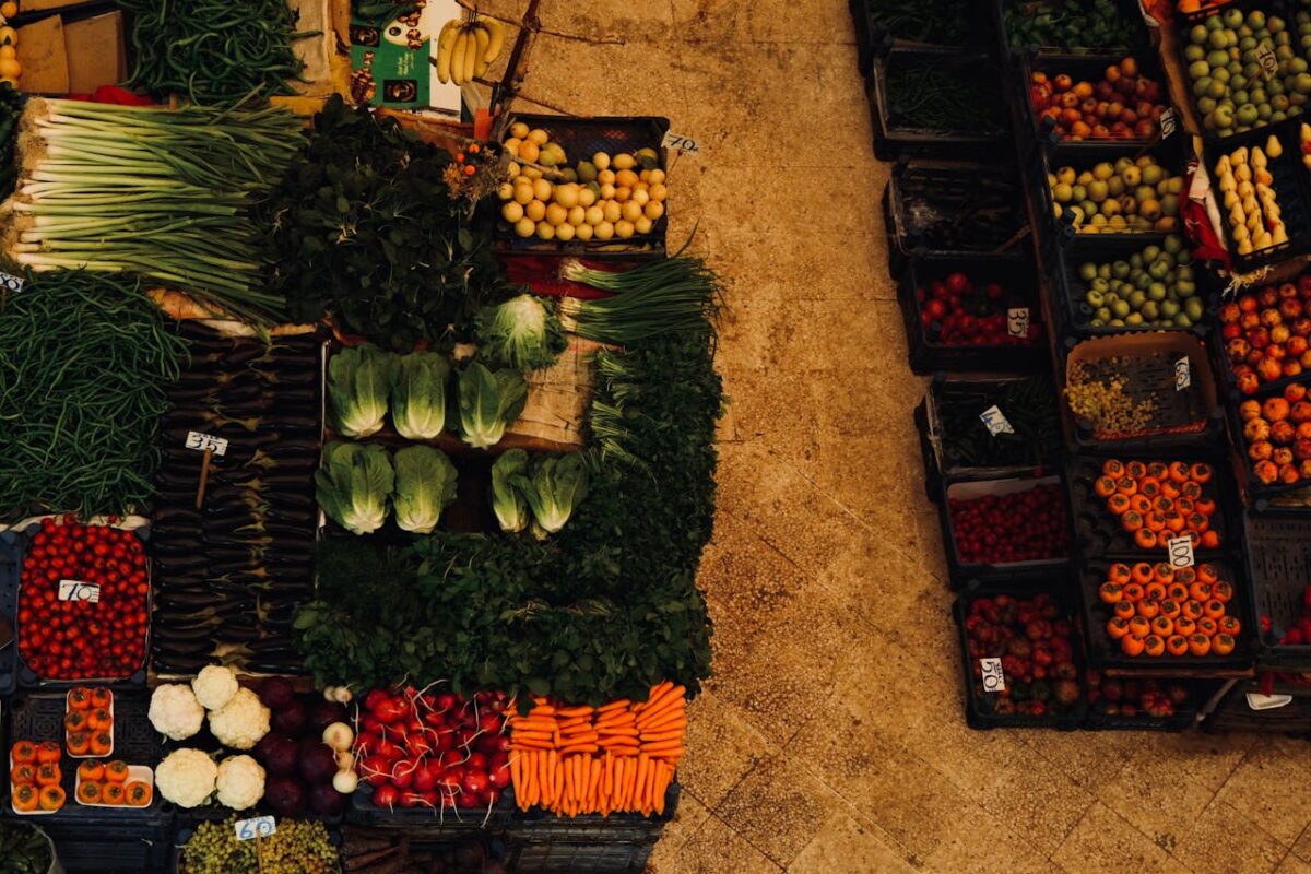 A vibrant aerial shot of a diverse array of fresh vegetables and fruits at a farmer's market.