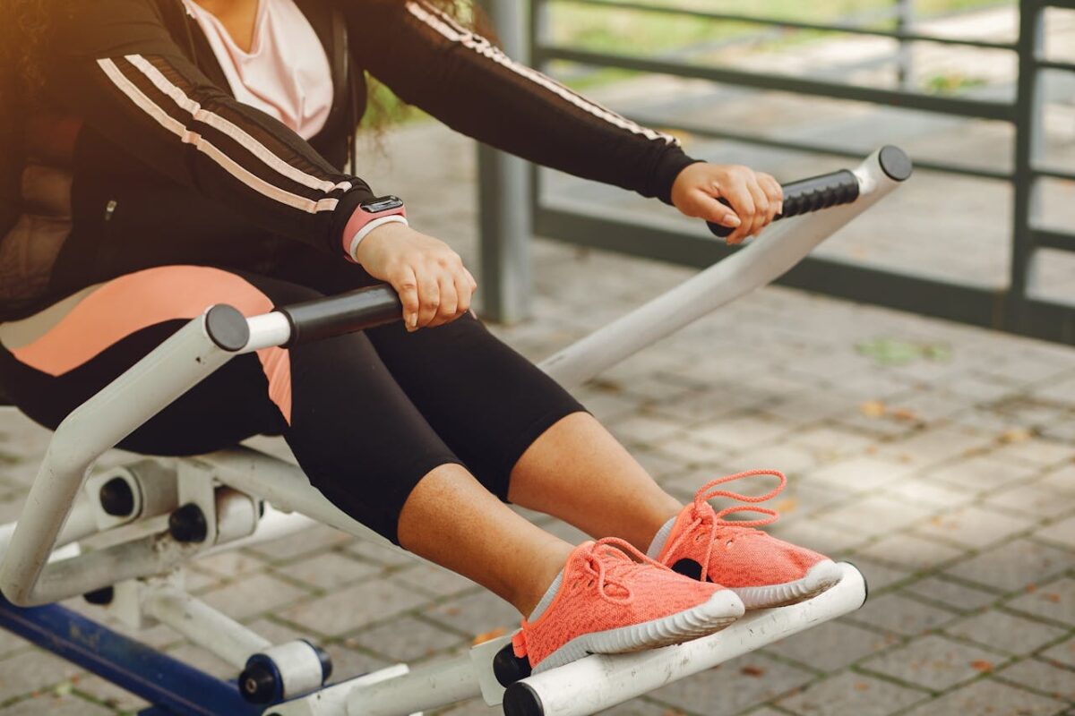 A woman in sportswear works out on outdoor fitness equipment, focusing on health and recreation.