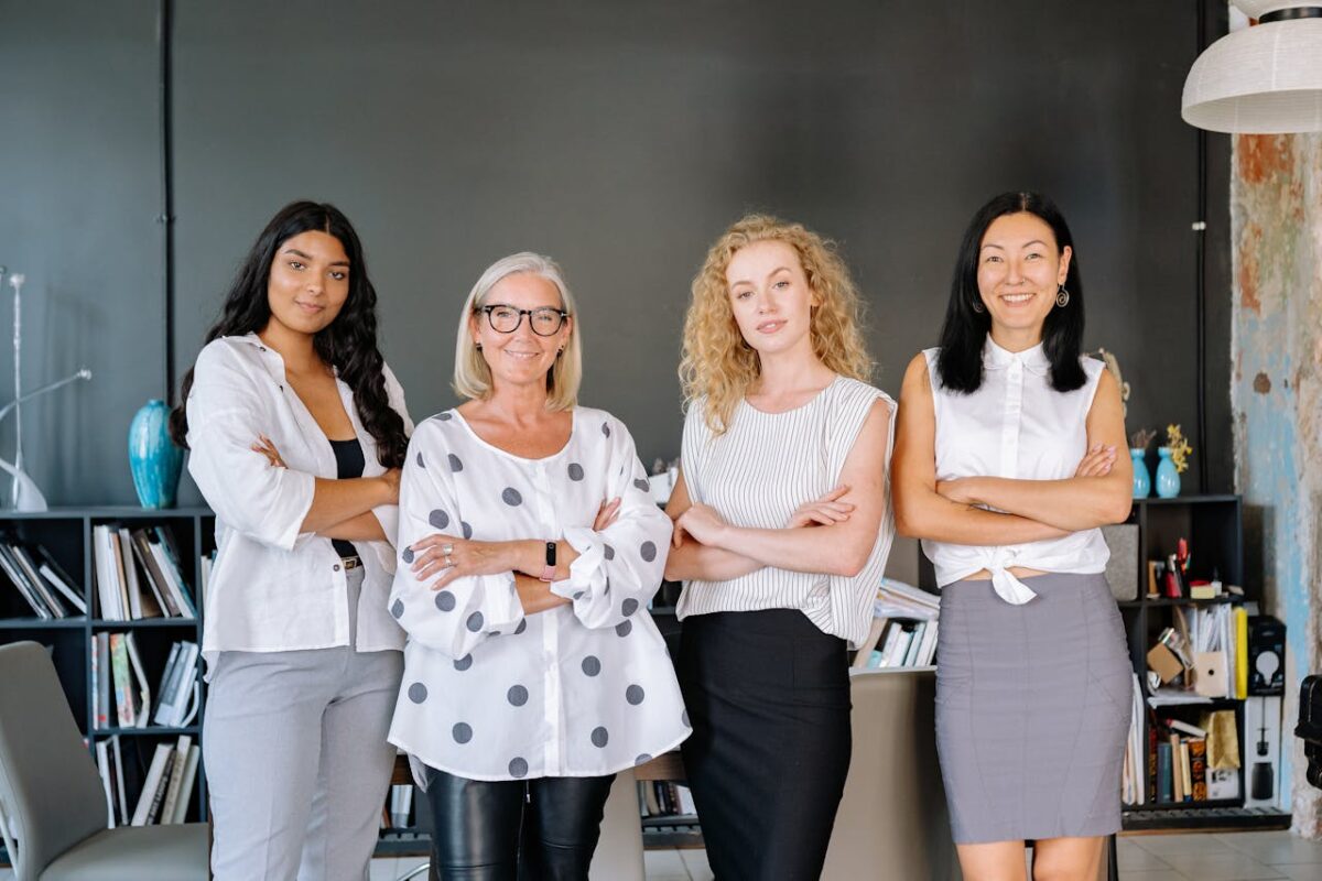 Four professional women standing confidently in an office, symbolizing diversity and teamwork.